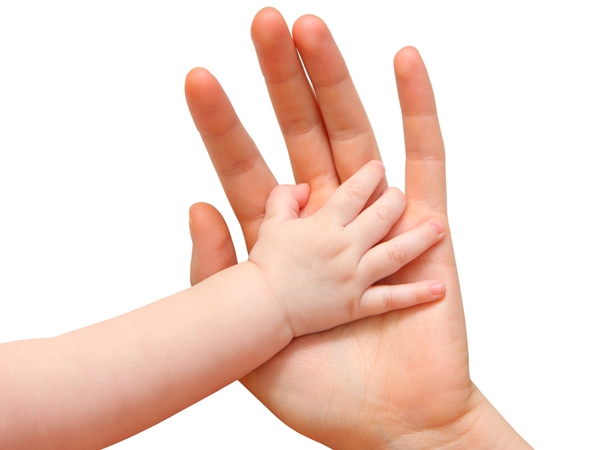 A baby holding a parent's hand.